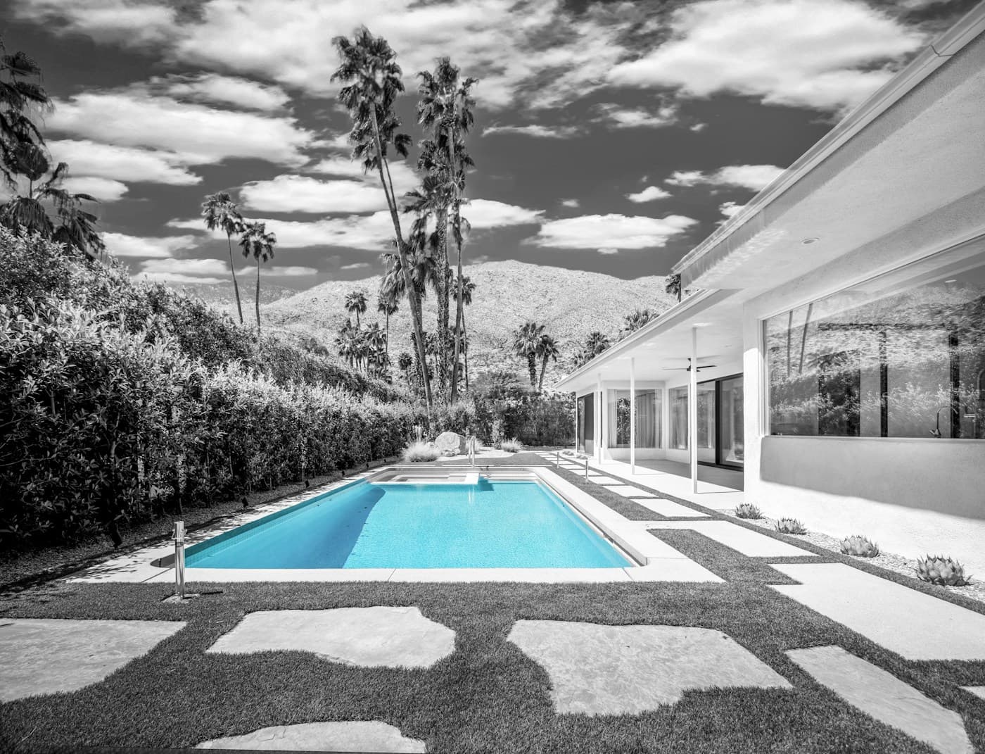 Modern home with a bright blue pool and desert mountains